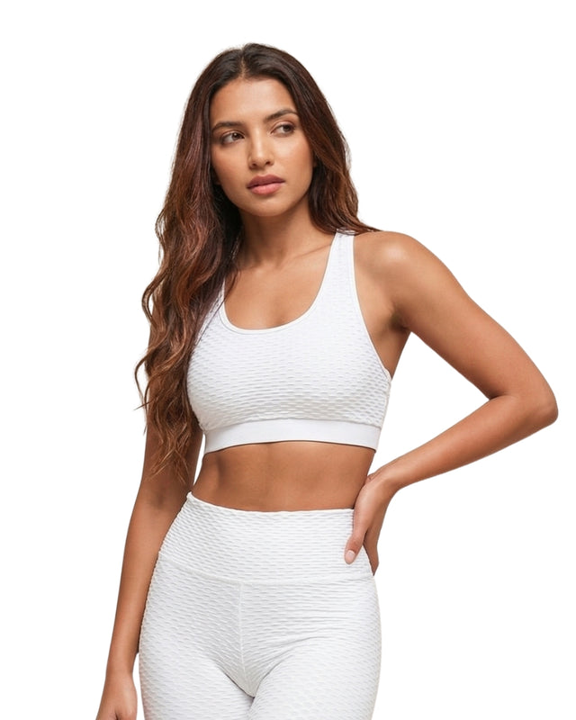 Woman wearing a white sports bra and leggings on a white background