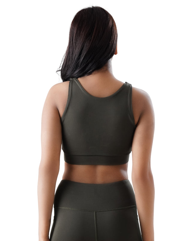 Person wearing a dark green sports bra and leggings on a white background