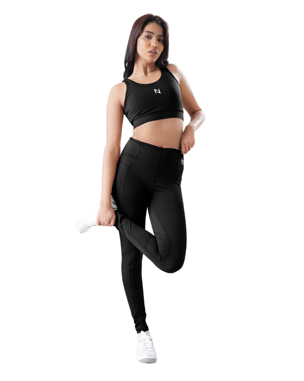 Woman in black athletic wear posing on a white background