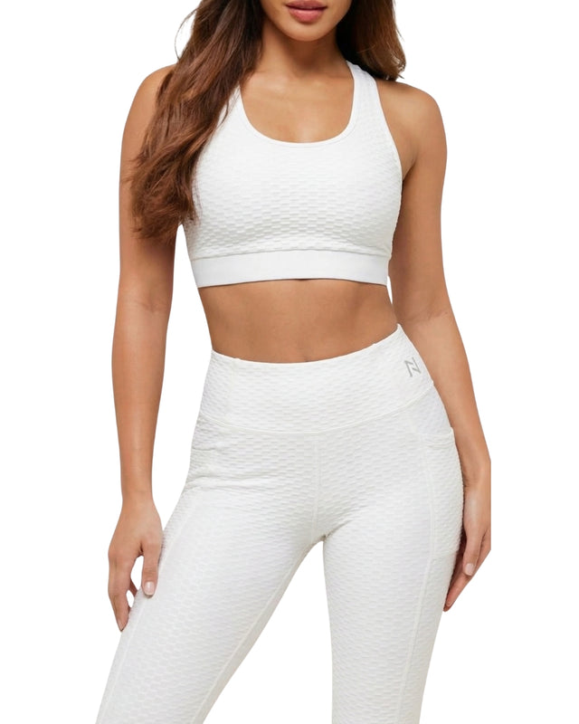 Woman wearing a white sports bra and leggings on a white background