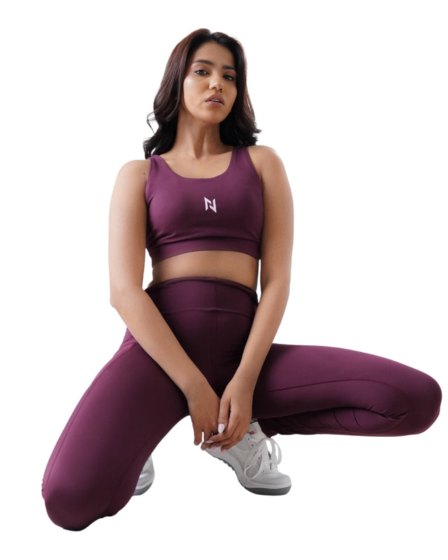 Woman wearing a purple athletic outfit with a logo on a white background