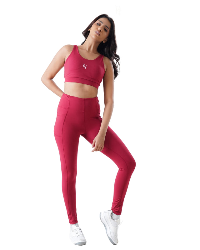 Woman wearing a pink sports bra and leggings set on a white background