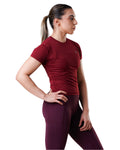 Woman wearing a red athletic shirt and maroon leggings on a white background