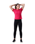 Woman wearing a pink athletic shirt and black leggings on a white background