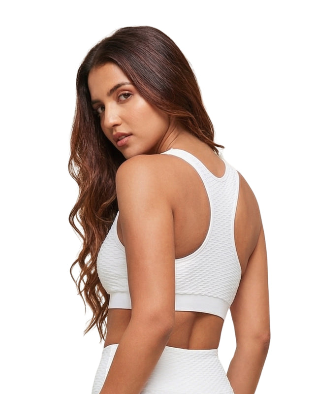 Woman wearing a white sports bra and leggings on a white background