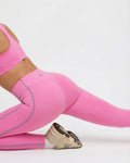Person wearing pink athletic leggings and sports bra on a white background
