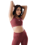 Woman wearing a maroon sports bra and leggings with a logo on a white background