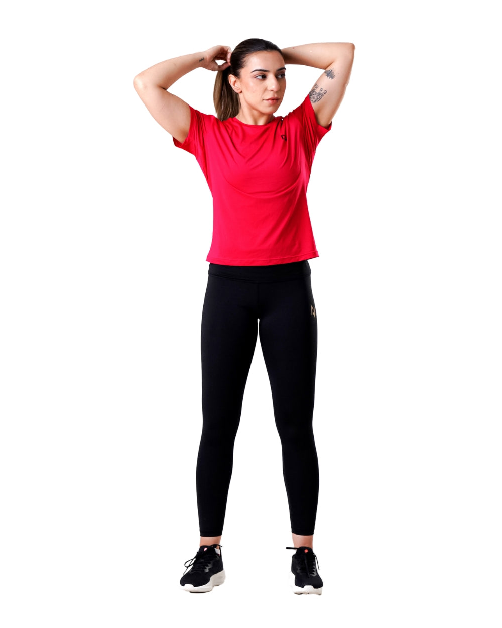 Woman wearing a red athletic shirt and black leggings on a white background
