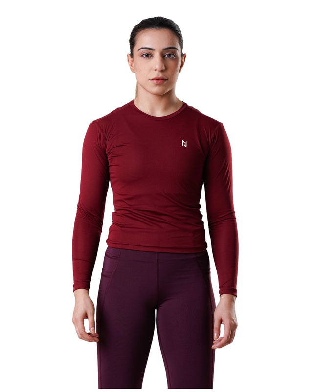 Person wearing a maroon long-sleeve athletic shirt and maroon leggings on a white background