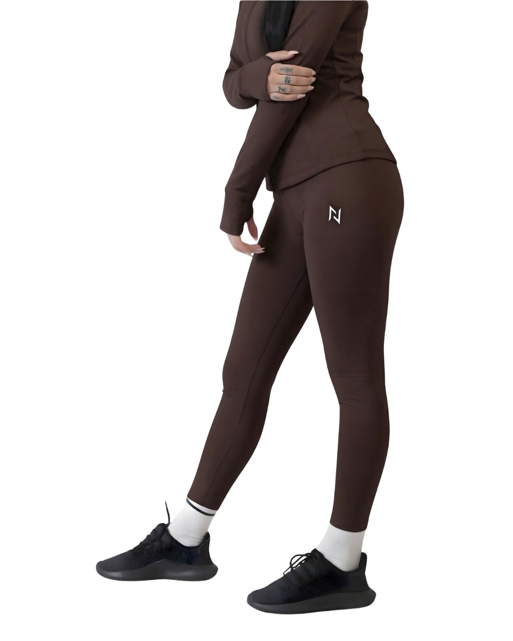 Person wearing a brown tracksuit with a logo on the leg, standing against a white background